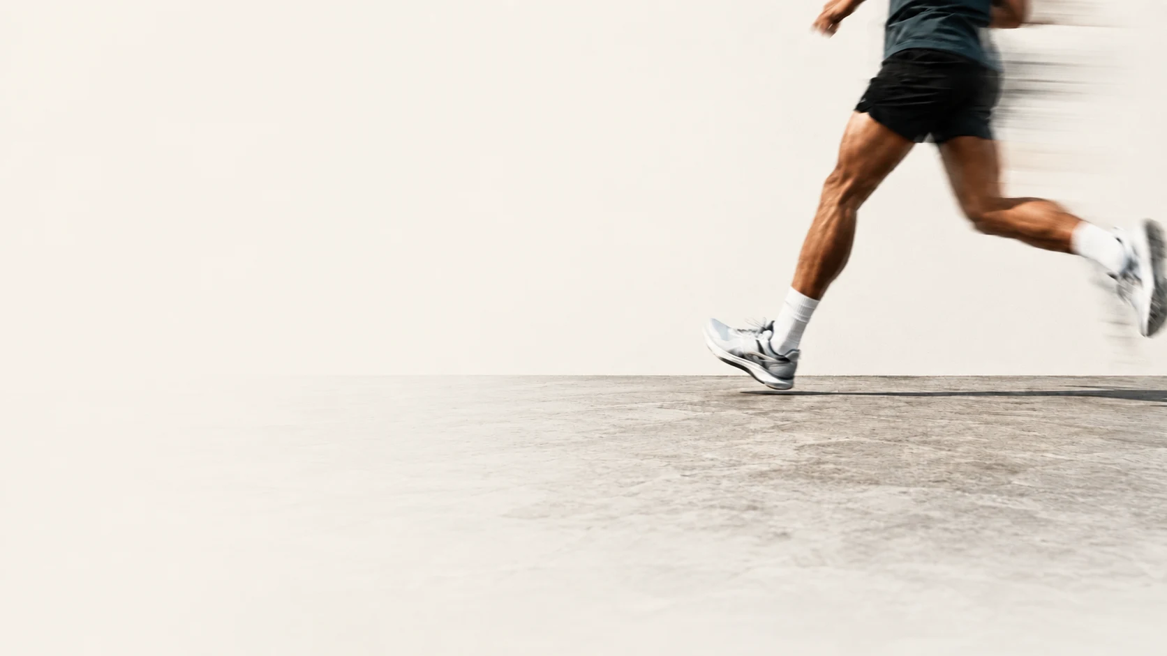 A runner captured mid-stride in motion blur, crossing an open concrete space.