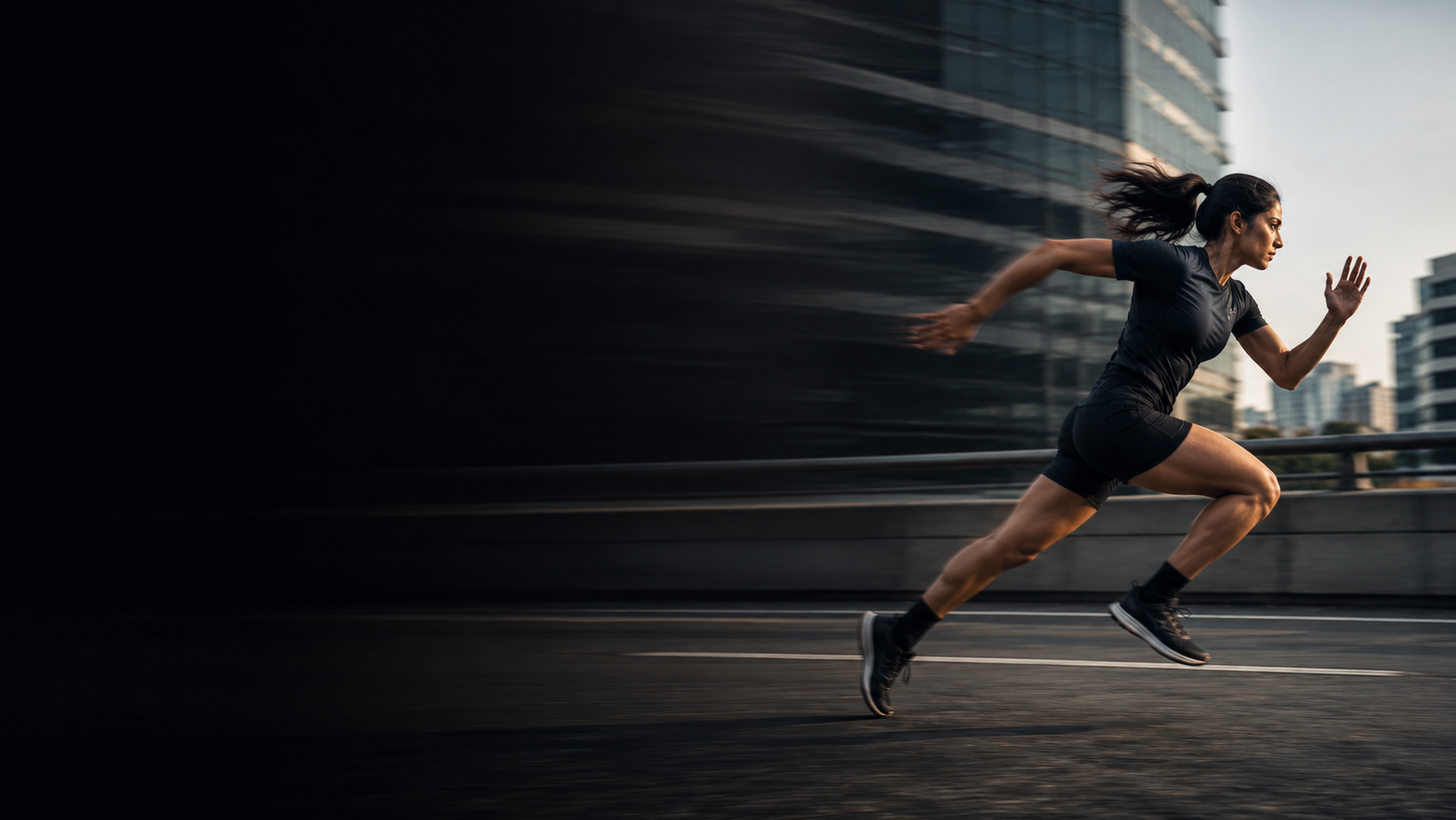 A sprinter at full stride on a city road, the background streaked with motion.